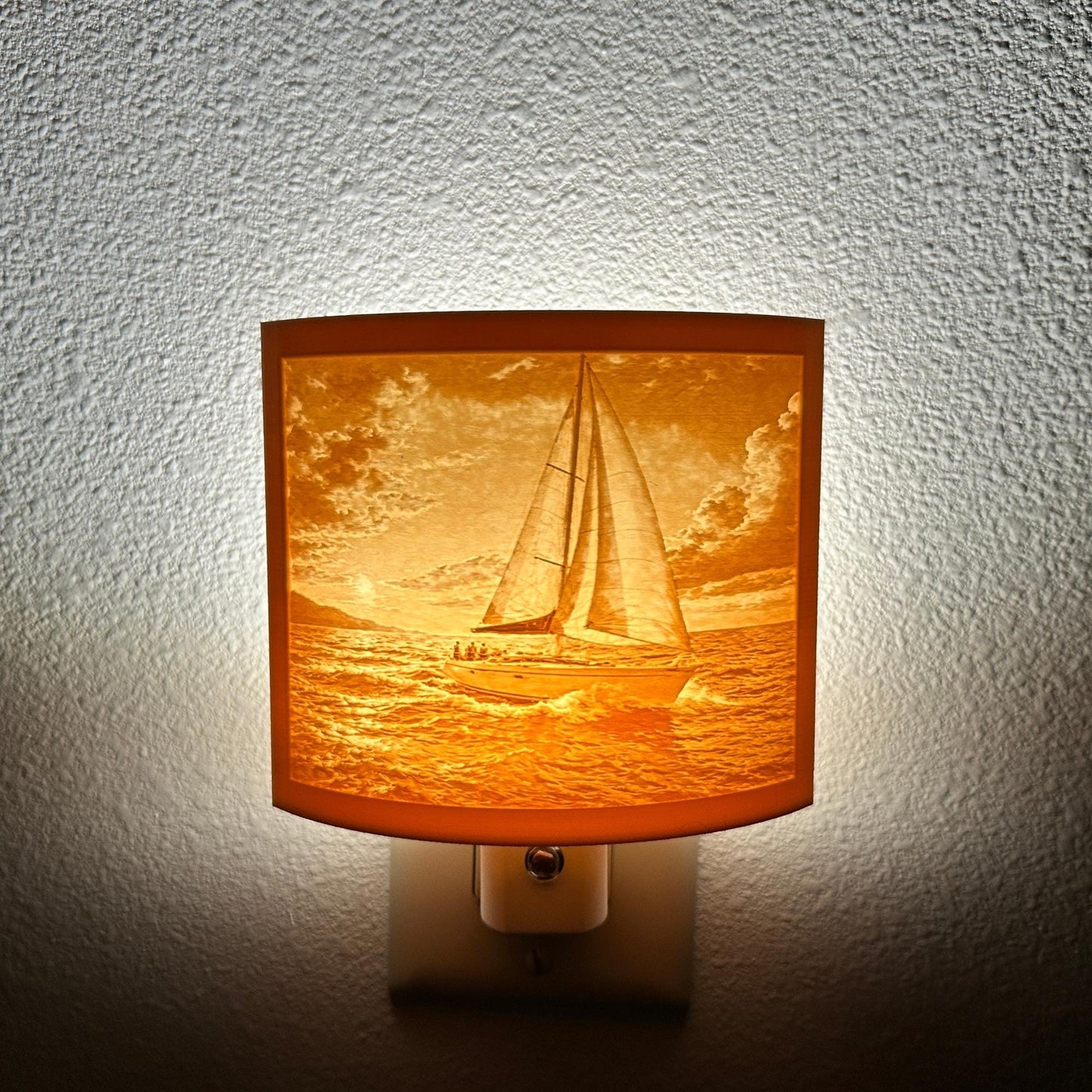 Warm glowing sailboat lithophane night light with detailed ocean waves and dramatic sunset sky, curved nautical lamp decor for coastal bedroom, hallway, or beach house ambiance.