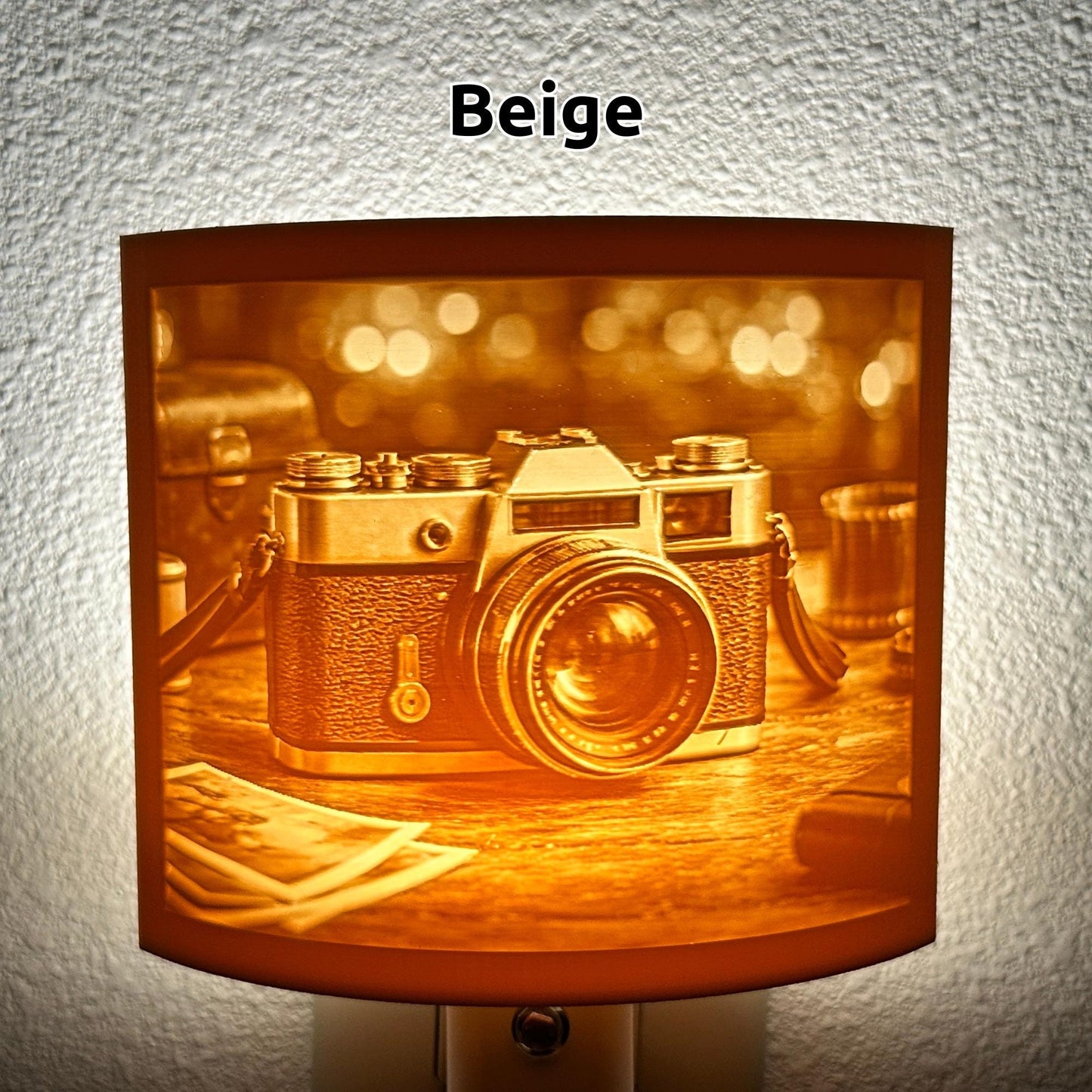 Warm glowing camera lithophane night light featuring a detailed vintage-style camera on a tabletop with blurred background lights, curved photography-themed decor for bedrooms, offices, studios, or camera lovers.