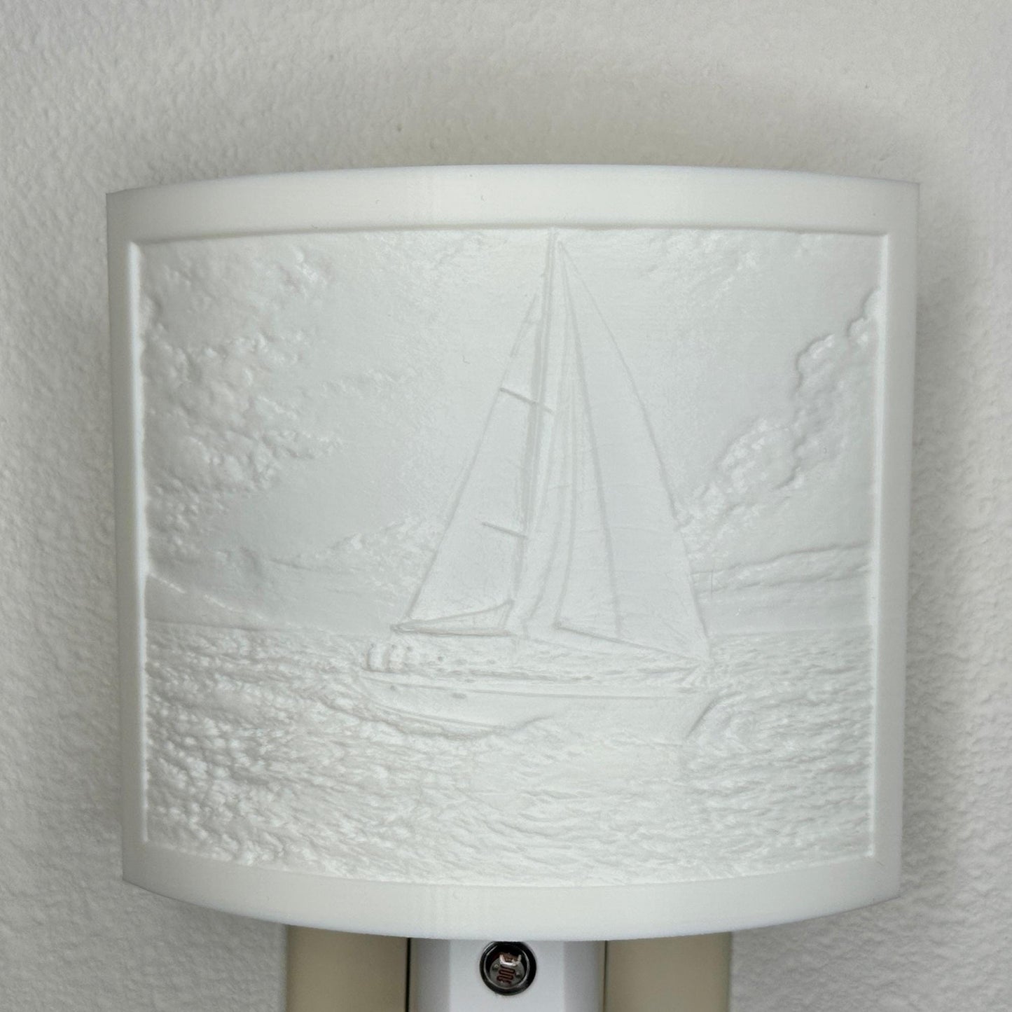 White sailboat lithophane night light with embossed sailing scene featuring ocean waves, clouds, and a detailed sailboat, curved nautical wall decor for coastal or beach-themed spaces.