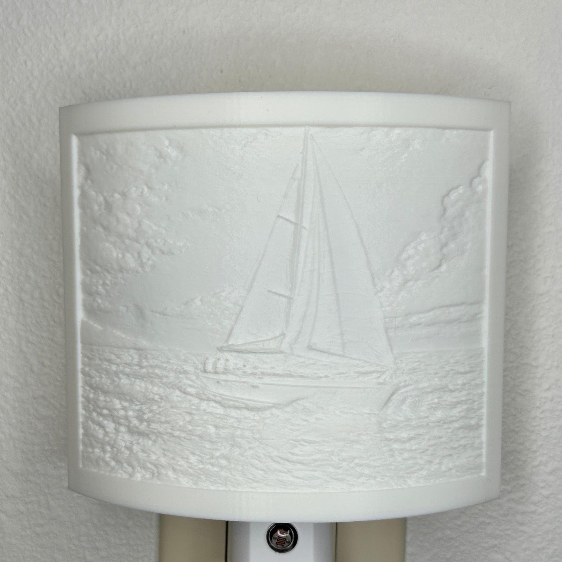 White sailboat lithophane night light with embossed sailing scene featuring ocean waves, clouds, and a detailed sailboat, curved nautical wall decor for coastal or beach-themed spaces.
