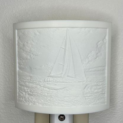 White sailboat lithophane night light with embossed sailing scene featuring ocean waves, clouds, and a detailed sailboat, curved nautical wall decor for coastal or beach-themed spaces.