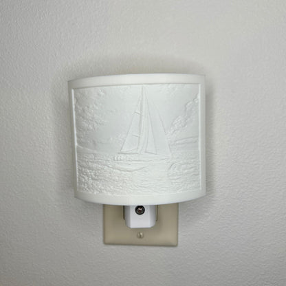 White sailboat lithophane night light with embossed sailing scene featuring ocean waves, clouds, and a detailed sailboat, curved nautical wall decor for coastal or beach-themed spaces.
