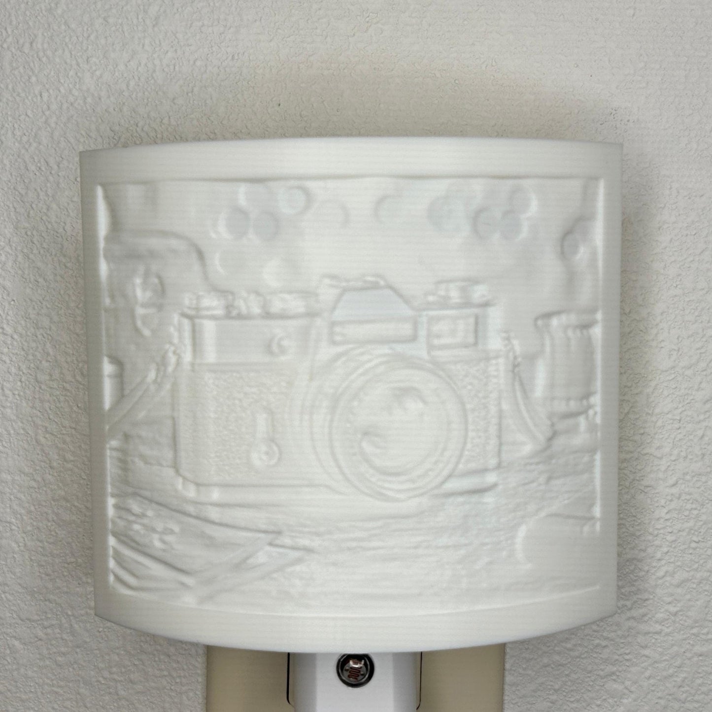 White camera lithophane night light with embossed vintage-style camera design on a tabletop scene, curved photography-themed decor for bedrooms, offices, studios, or camera enthusiasts.