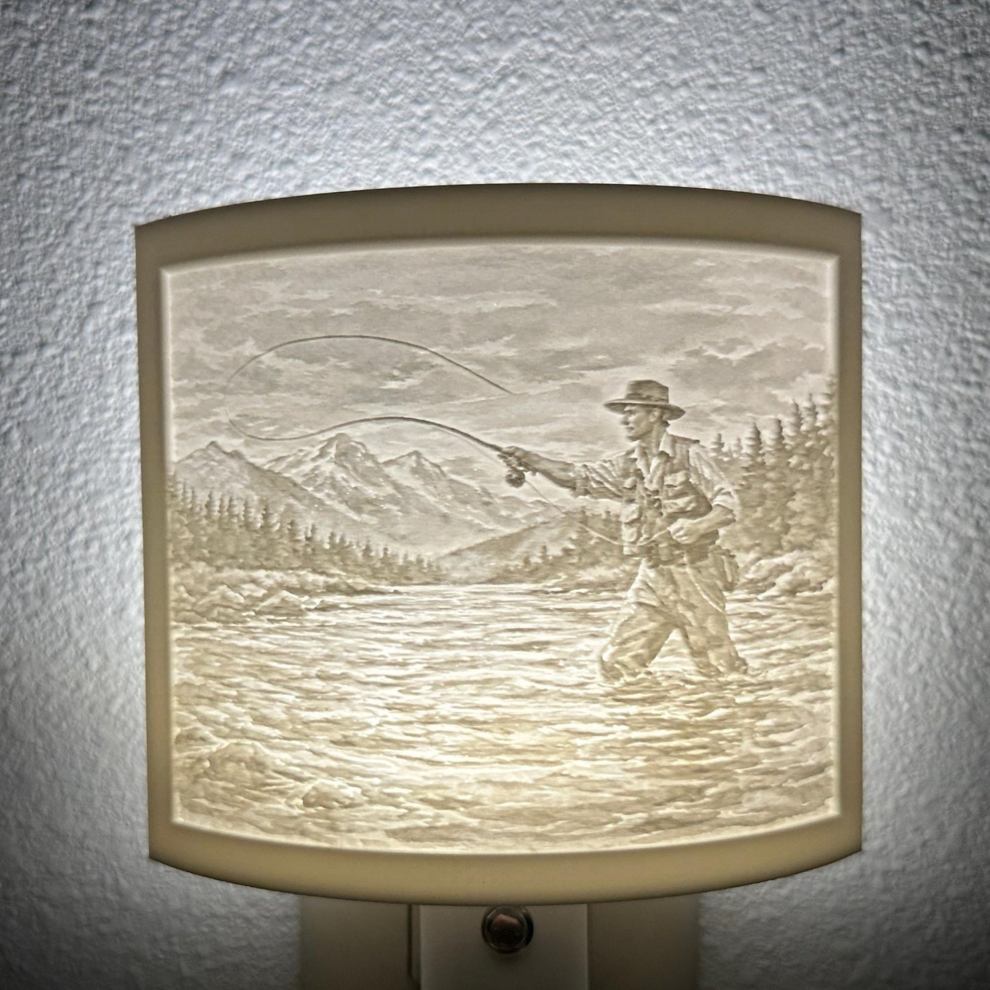 White fishing lithophane night light featuring a fly fisherman casting in a mountain river with forest and mountain scenery, softly glowing curved outdoor-themed decor for cabins, lodges, fishing enthusiasts, or rustic spaces.