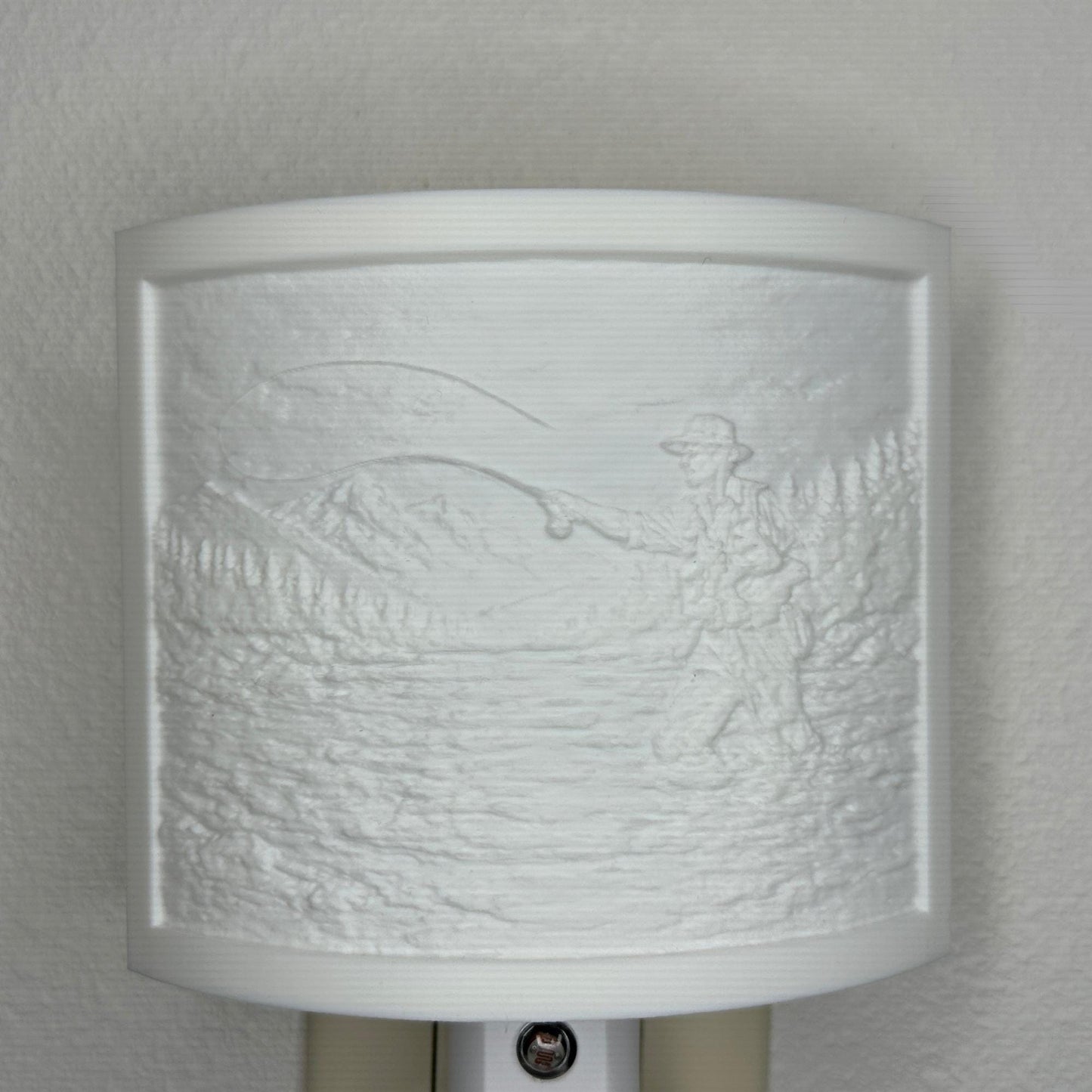 White fishing lithophane night light with embossed fly fisherman casting in a mountain river surrounded by forest and mountain scenery, curved outdoor-themed decor for cabins, lodges, fishing enthusiasts, or rustic spaces.