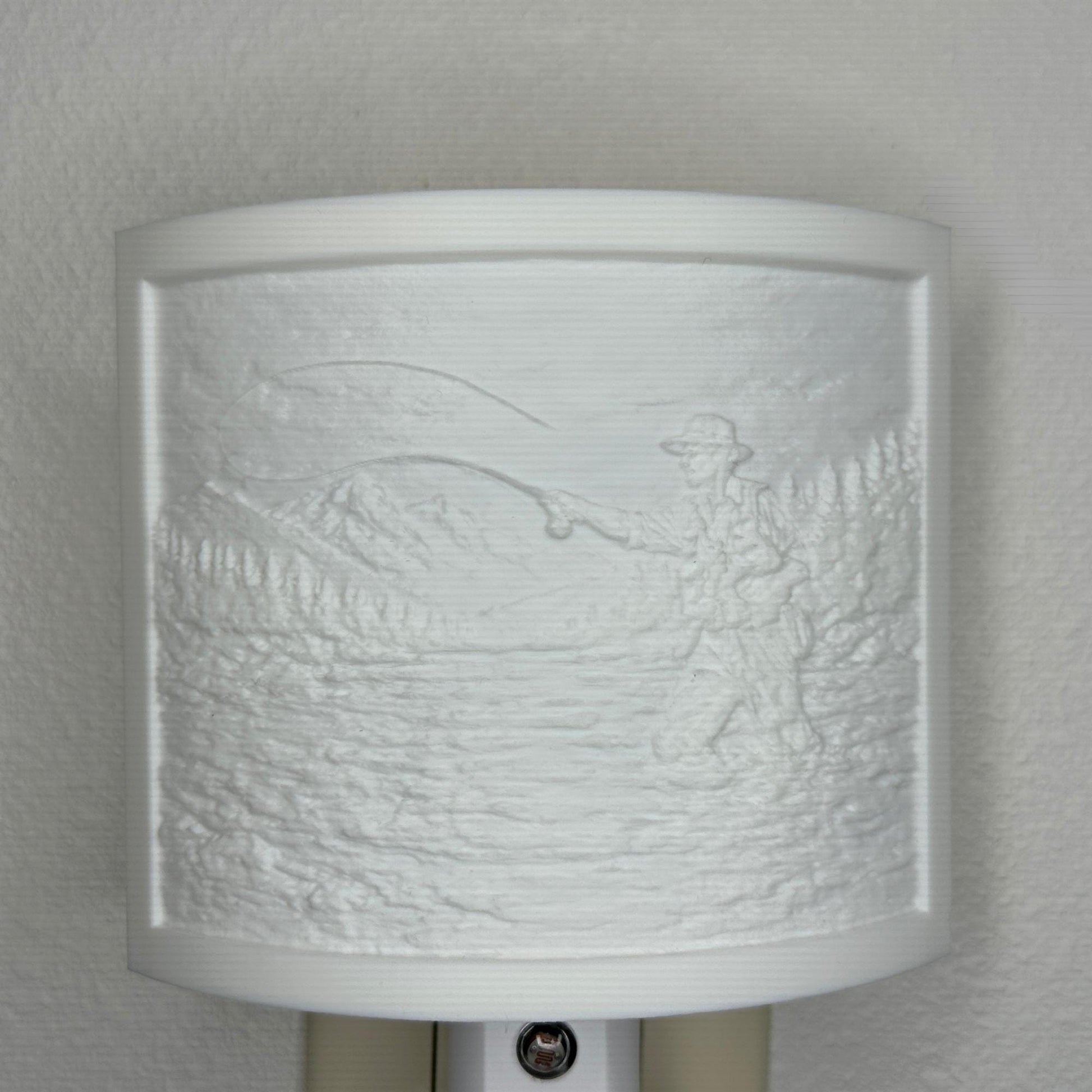 White fishing lithophane night light with embossed fly fisherman casting in a mountain river surrounded by forest and mountain scenery, curved outdoor-themed decor for cabins, lodges, fishing enthusiasts, or rustic spaces.