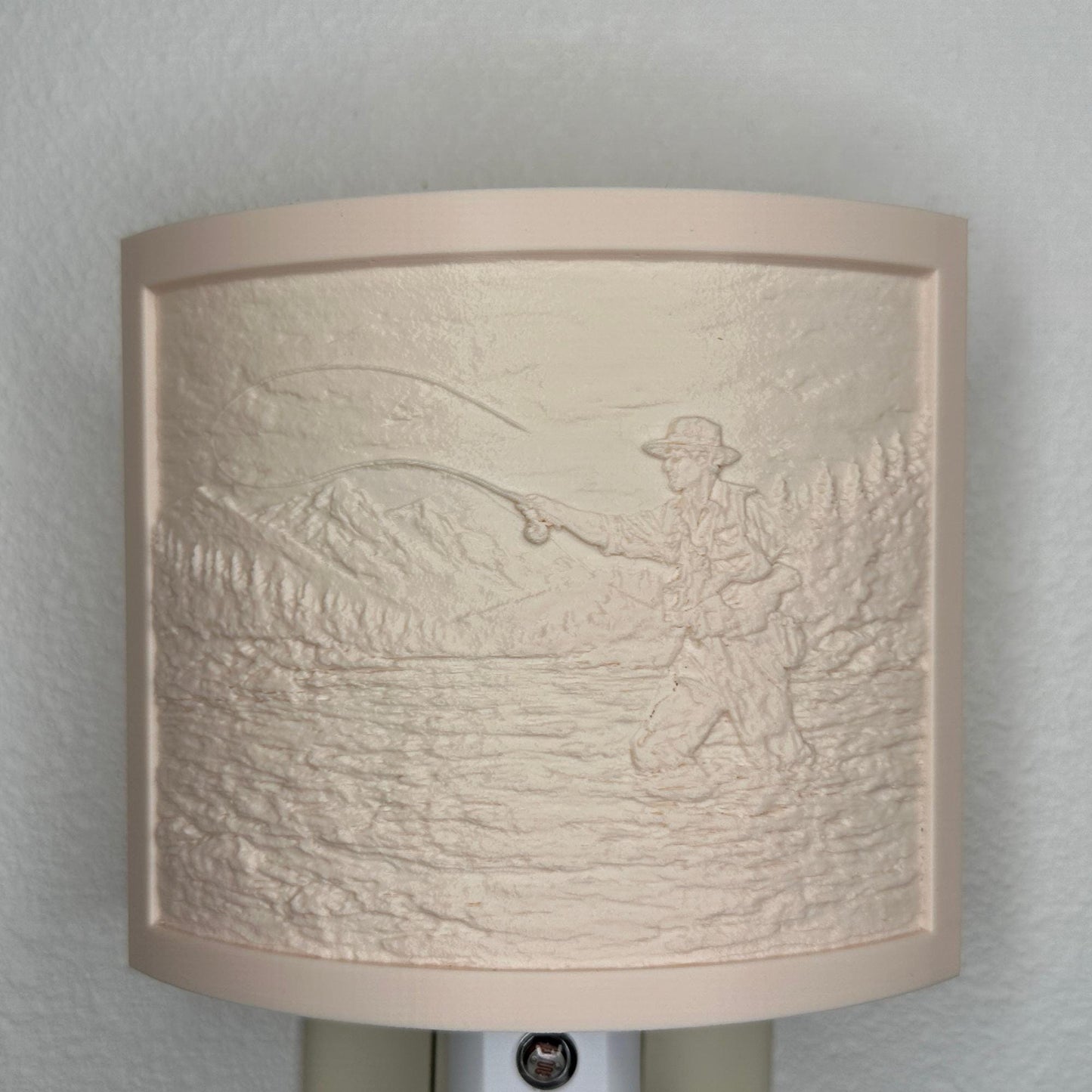 Beige fishing lithophane night light with embossed fly fisherman casting in a mountain river surrounded by forest and mountain scenery, curved outdoor-themed decor for cabins, lodges, fishing enthusiasts, or rustic spaces.